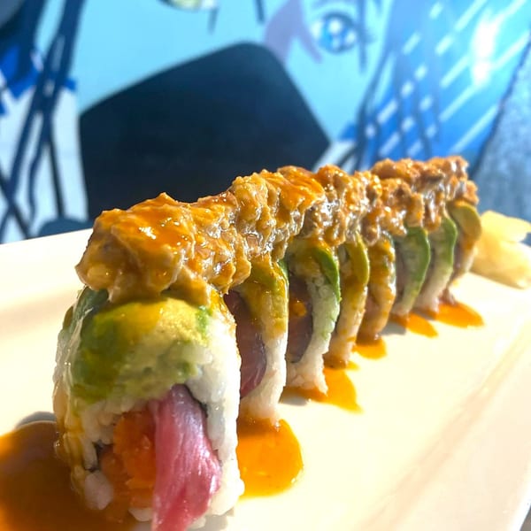 Sushi 4 Reel's sushi roll with avocado, tuna, and orange sauce on a white plate.