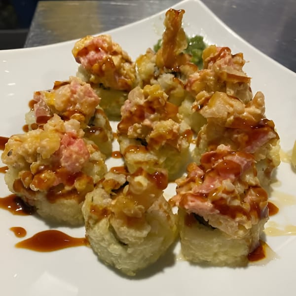 A plate of Sushi 4 Reel's fried sushi rolls topped with pink and yellow fish, drizzled with sauce.