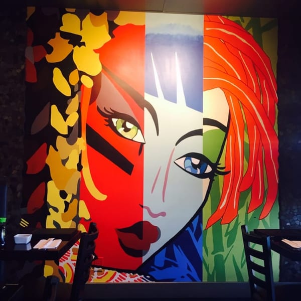 A vibrant, pop art style mural of a woman's face in bold colors adorns the restaurant wall.