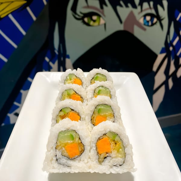 Sushi 4 Reel's sweet potato and cucumber sushi rolls on a white plate with anime art in the background.