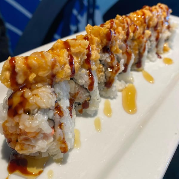 Sushi 4 Reel's crispy sushi roll with white rice, topped with orange sauce and dark drizzle.
