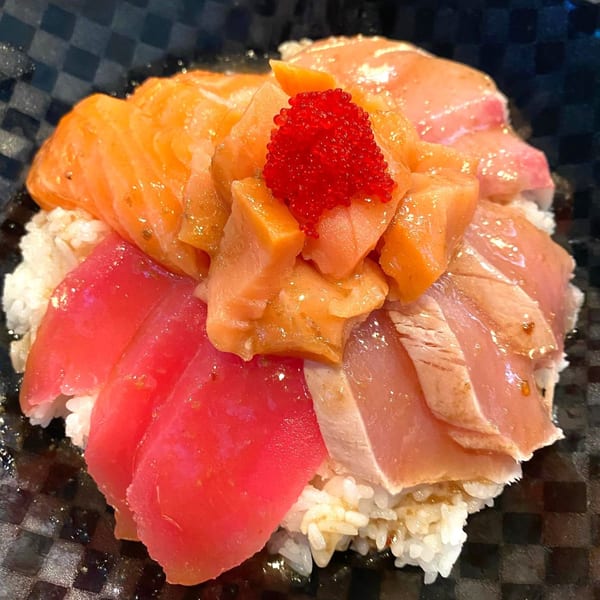 A colorful chirashi bowl with salmon, tuna, and other fish, topped with red tobiko.